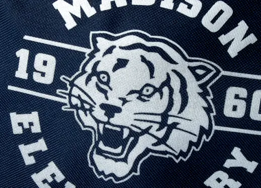 close up of reflective school mascot design on navy garment